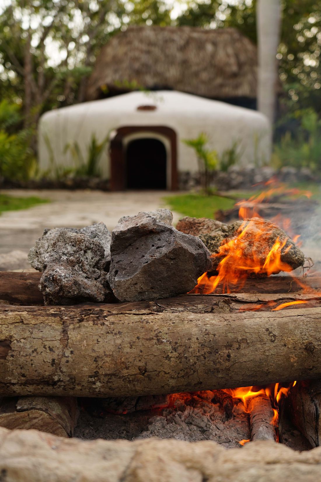 Temazcal de barro junto al fuego con piedras volcánicas